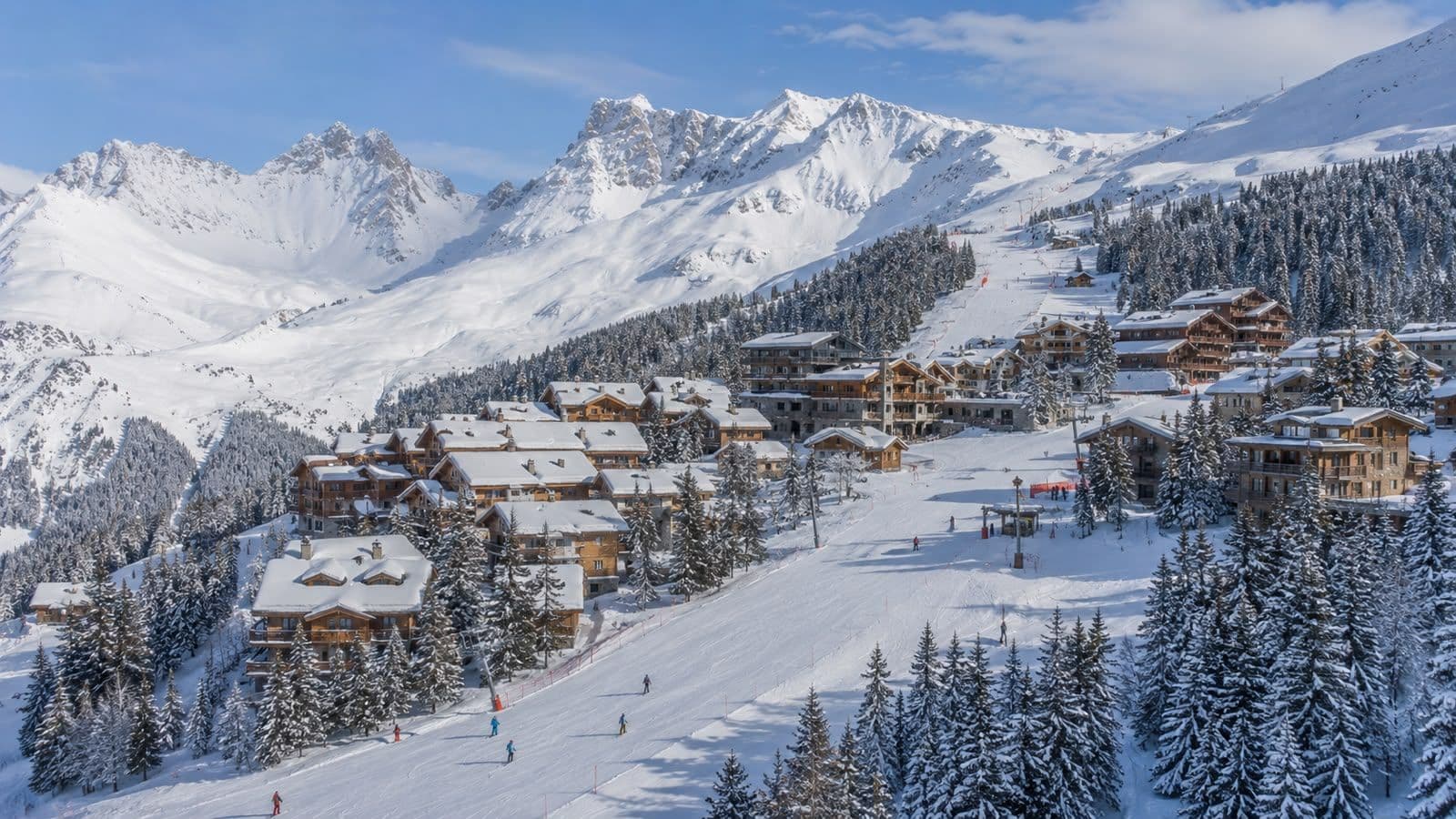 Panoramic view of Courchevel’s luxury ski resort with snow-covered chalets and Alpine mountain peaks.