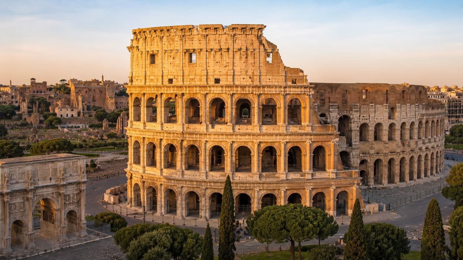 anoramic view of the Colosseum in Rome, illuminated by golden light with the Roman Forum and Arch of Constantine nearby.