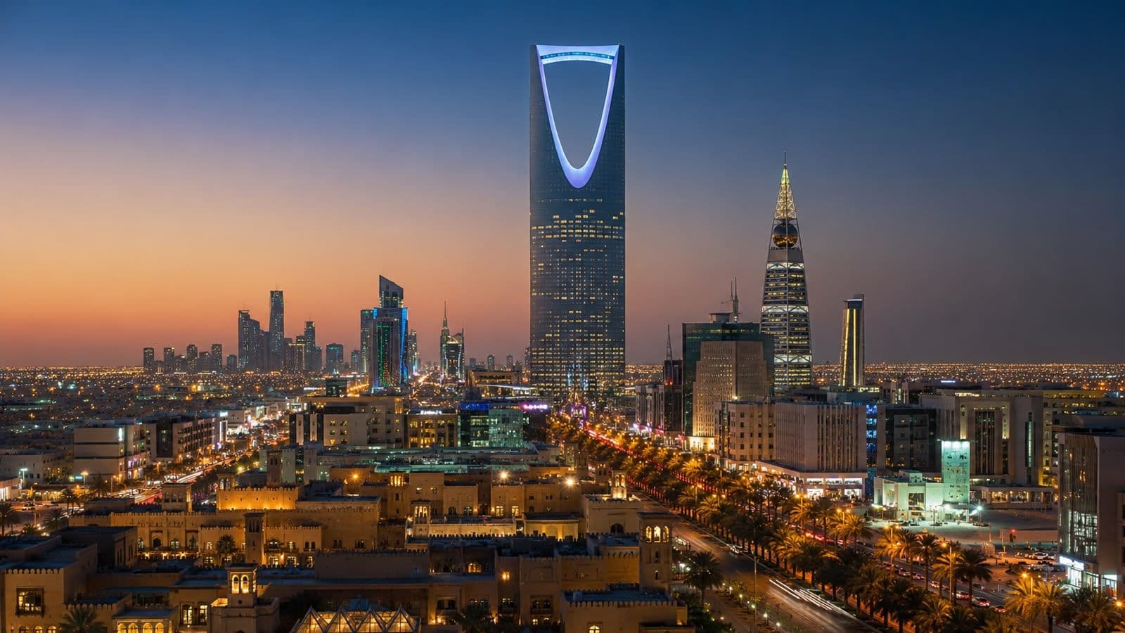 Riyadh skyline at sunset, showcasing the iconic Kingdom Centre Tower rising above the city's modern business district.